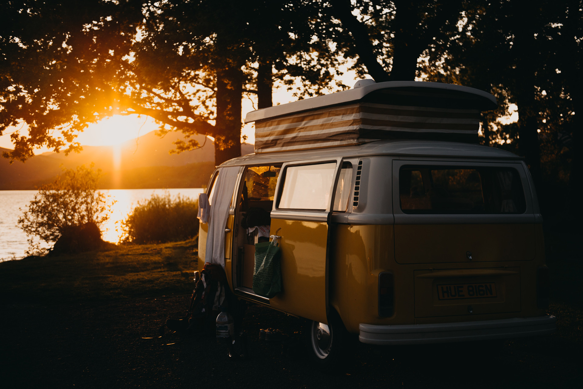 Orange VW campervan by a river at sunset
