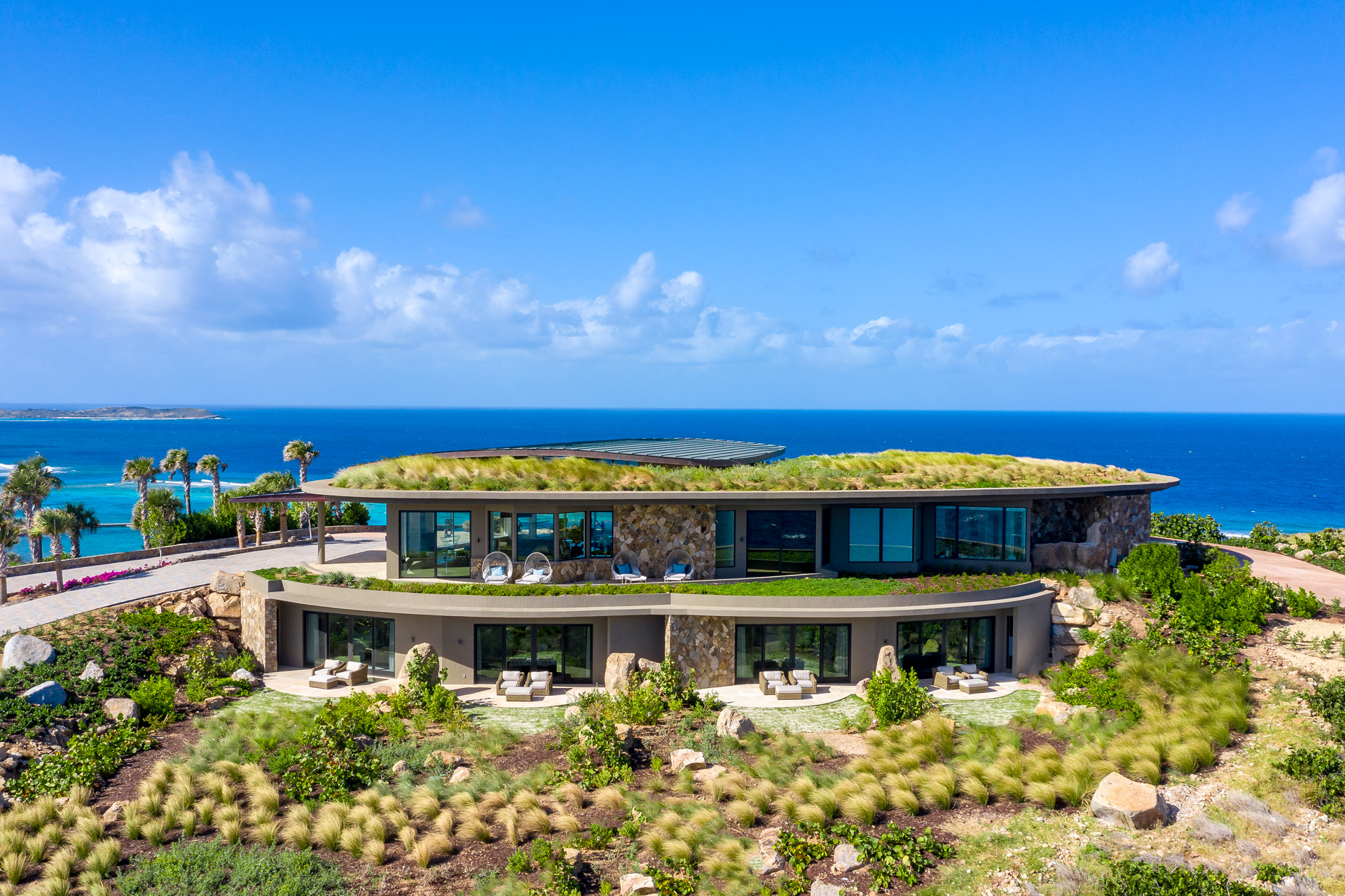 Coastal mansion with a green roof and floor-to-ceiling windows.
