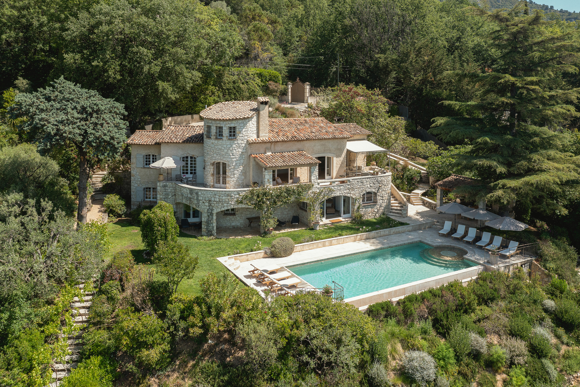 Aerial view of a French holiday home with an outdoor pool and trees surrounding