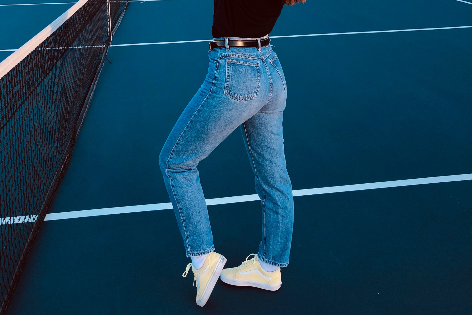 Close up of lower half in blue jeans on tennis court