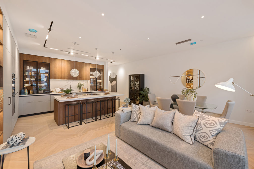 Large open-plan contemporary kitchen and living space with grey accents and dark wooden cabinets.