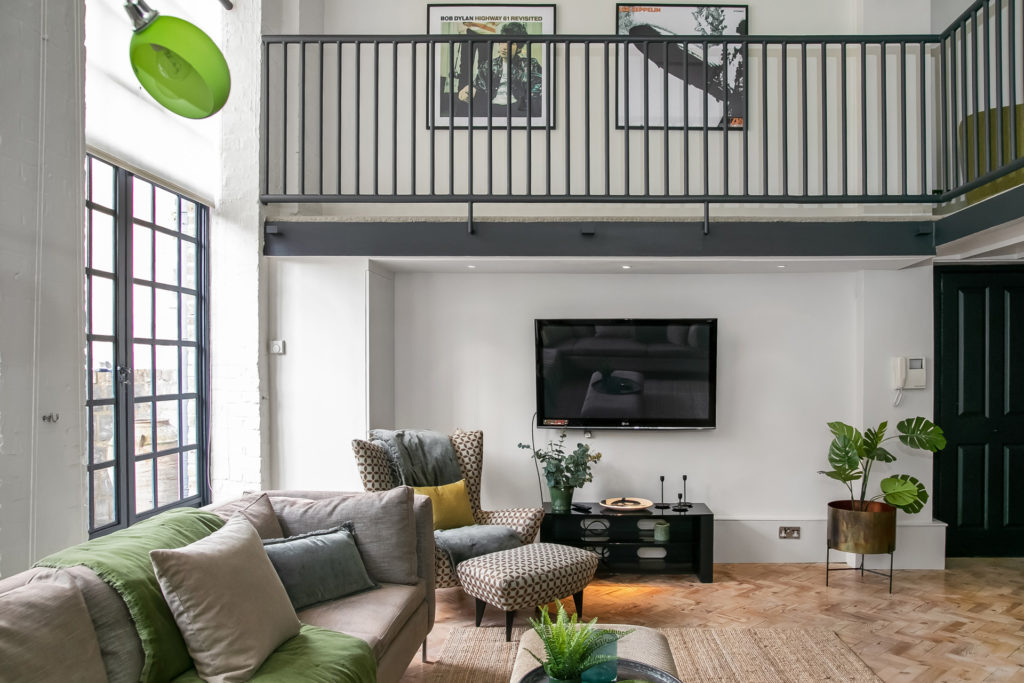 Warehouse conversion apartment with wooden flooring, large corner sofa and a mezzanine.