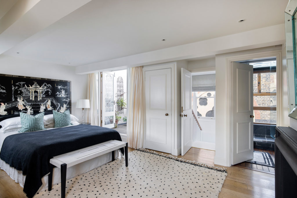 Modern bedroom with navy bedding and a white rug.