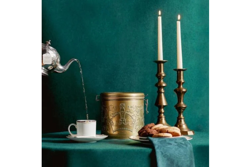 Gold tin next to tea cup and candles