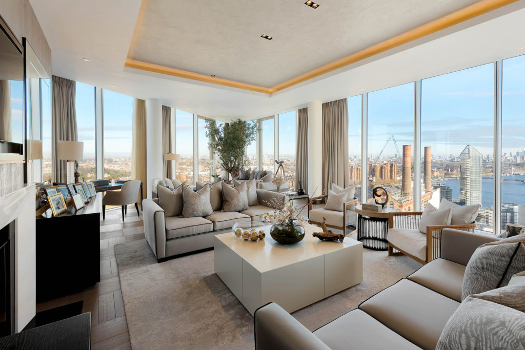 Large penthouse apartment with beige and cream furnishings and floor-to-ceiling windows.