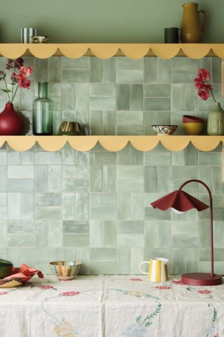 Green wall with yellow shelves and cloth-covered table