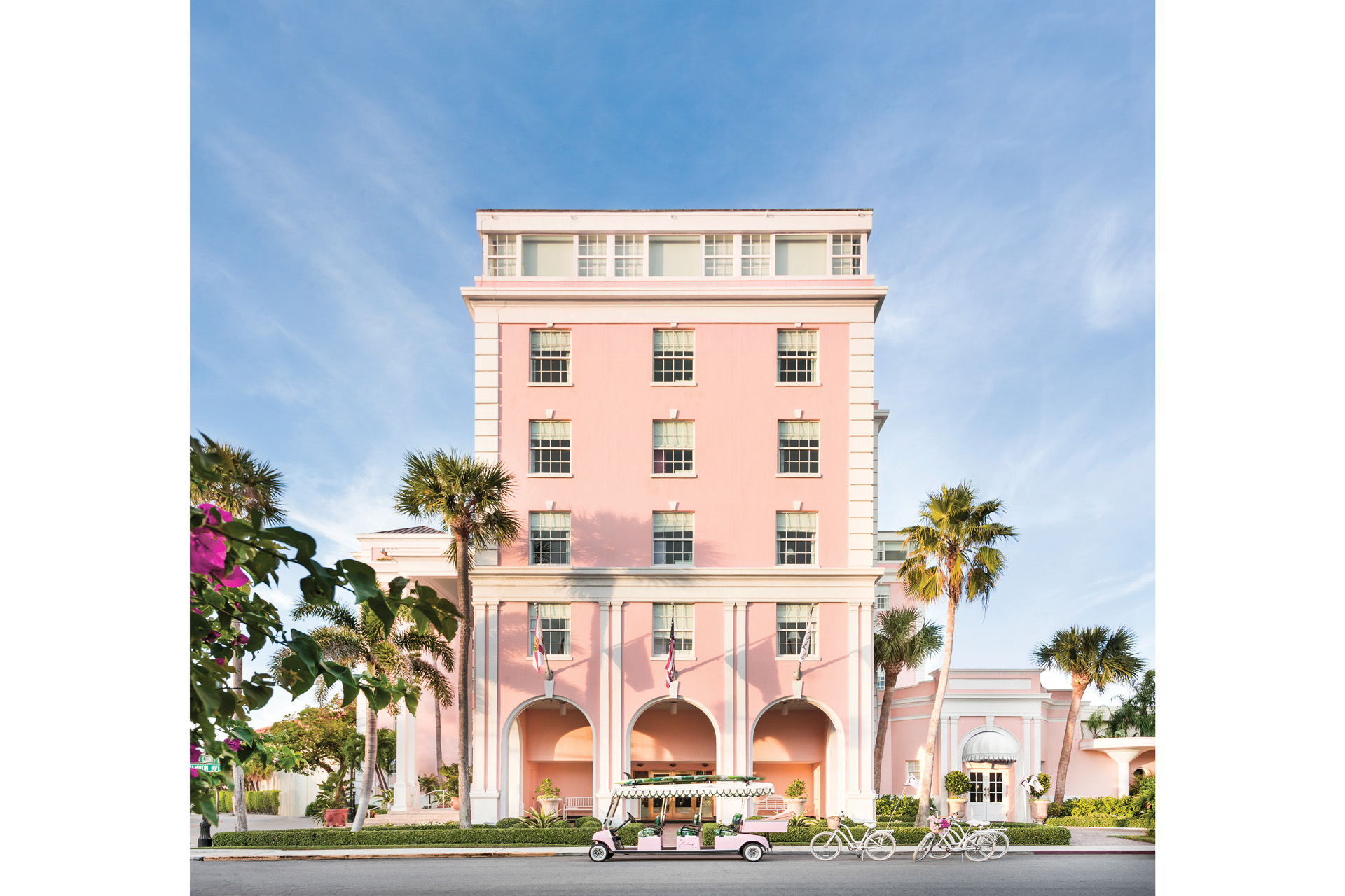 The tall facade of The Colony Palm Beach with a pink golf buggy