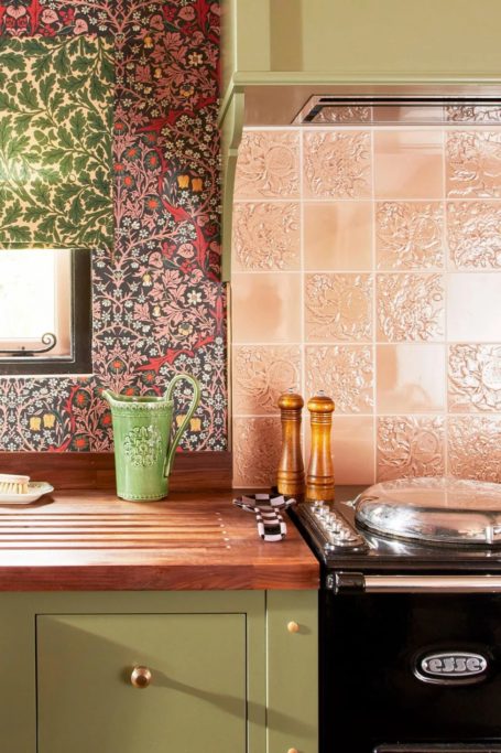 Kitchen with green cabinets, floral wallpaper and pink tiles