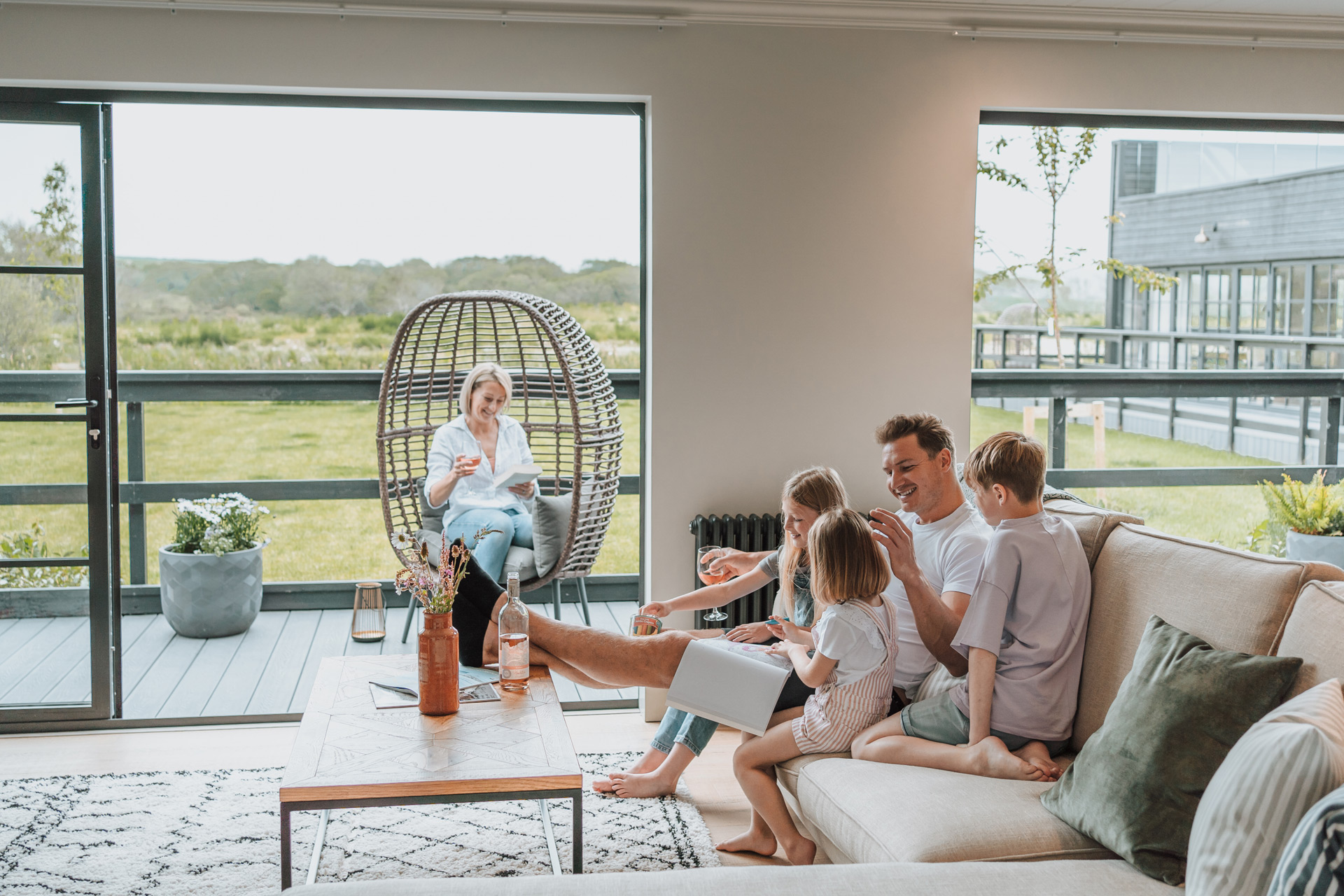 Family sitting on cream sofa in holiday home overlooking the countryside.