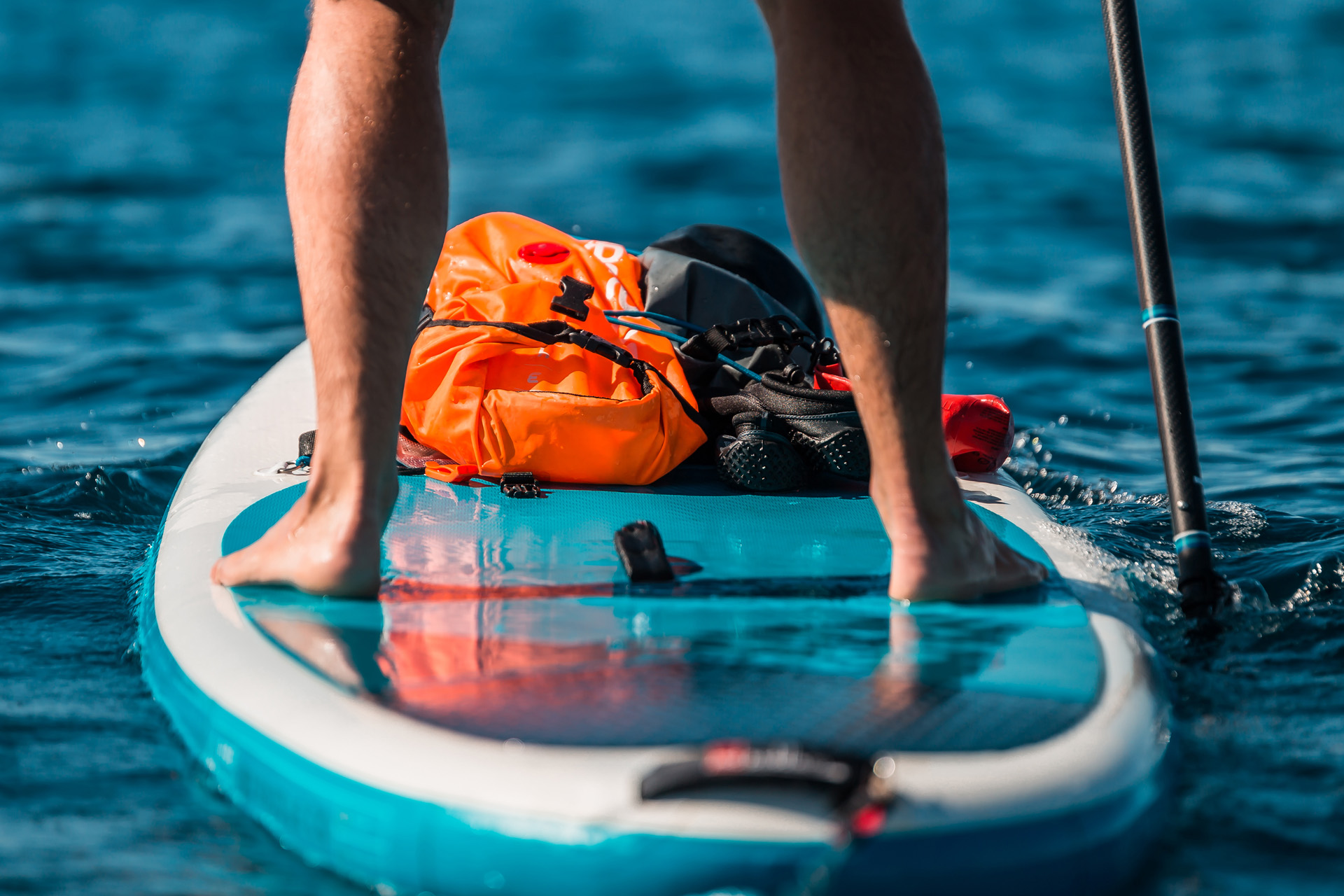 Young athletic man paddling on a SUP stand up paddle board in blue water sea in Montenegro