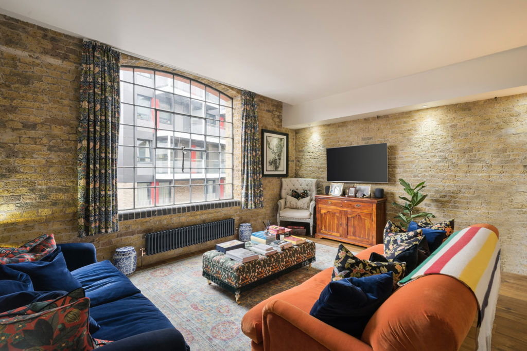 Warehouse apartment with Crittall windows and orange and blue velvet sofas.