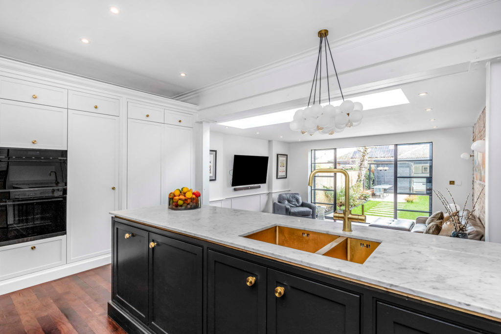 Modern kitchen with navy island, white units and white marble worktops.