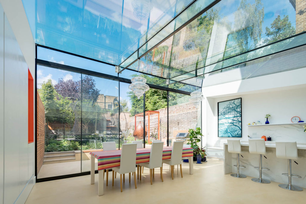 Full-width glass kitchen extension with sliding glass doors and glass ceilings.