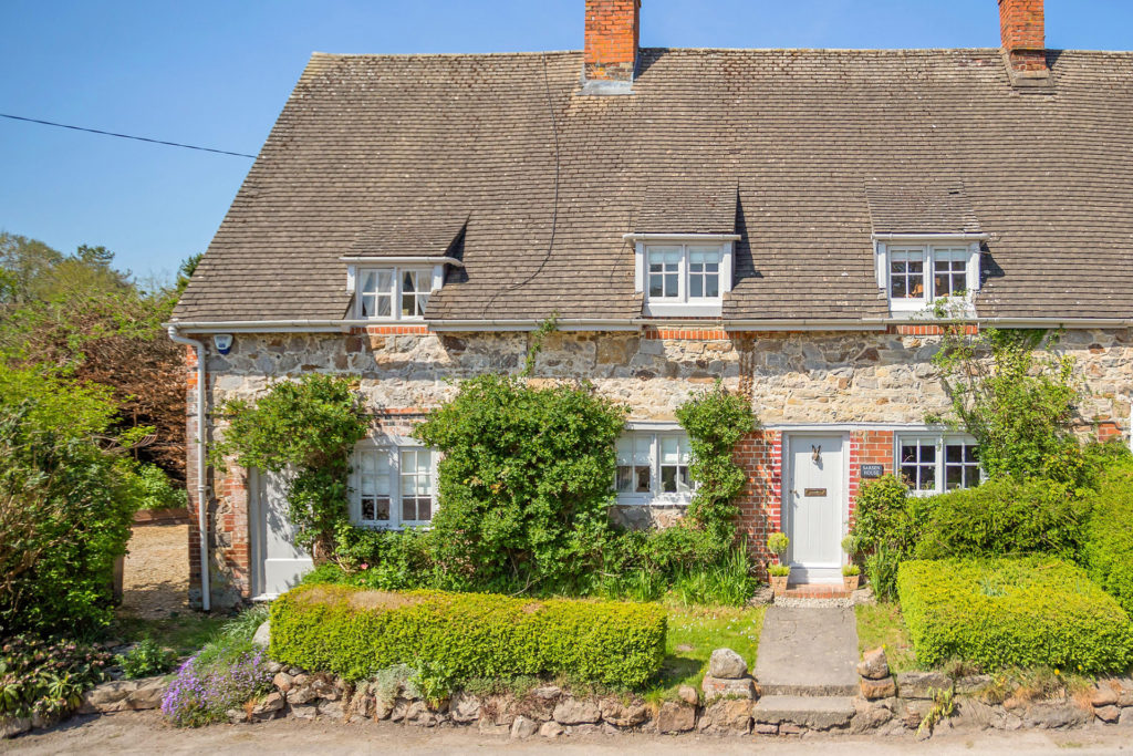 Brick cottage with ivy-clad walls and box hedges in front.