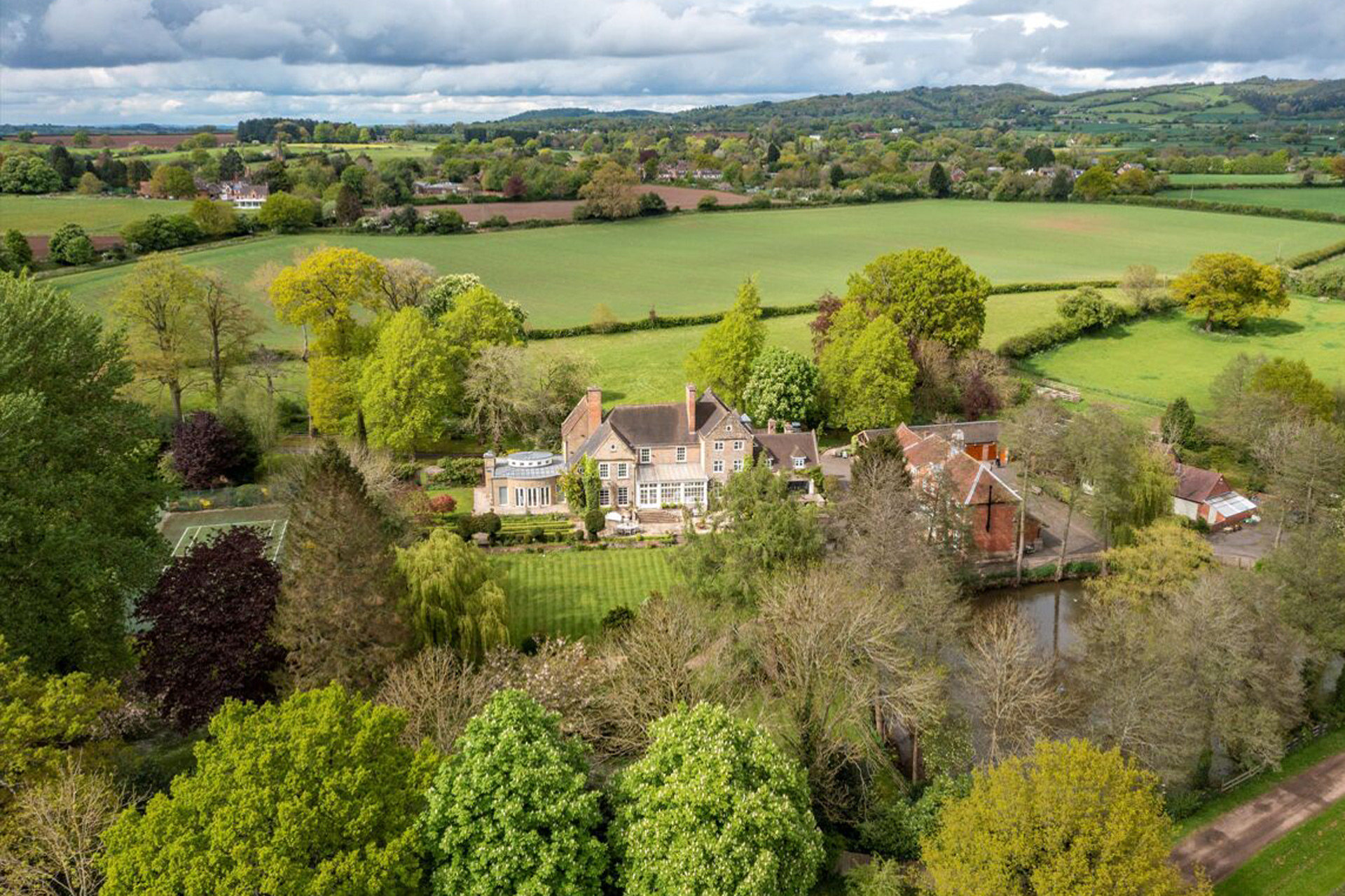 Aerial view of large country estate with tennis court, outbuildings and paddocks.