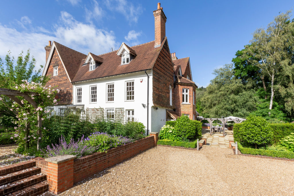 Gravel garden with lawns and a large country house behind.