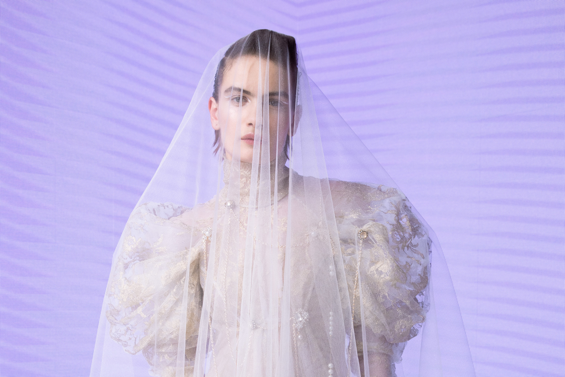 Woman in wedding dress and veil in front of purple background