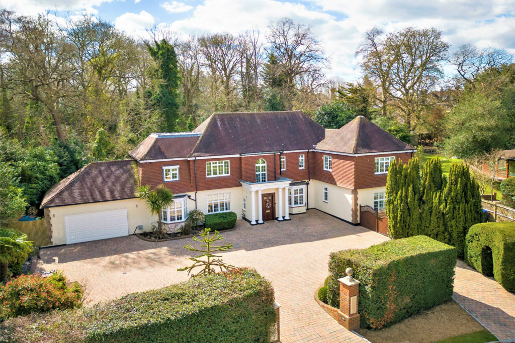 Large red brick family home with gravel driveway and box hedges.