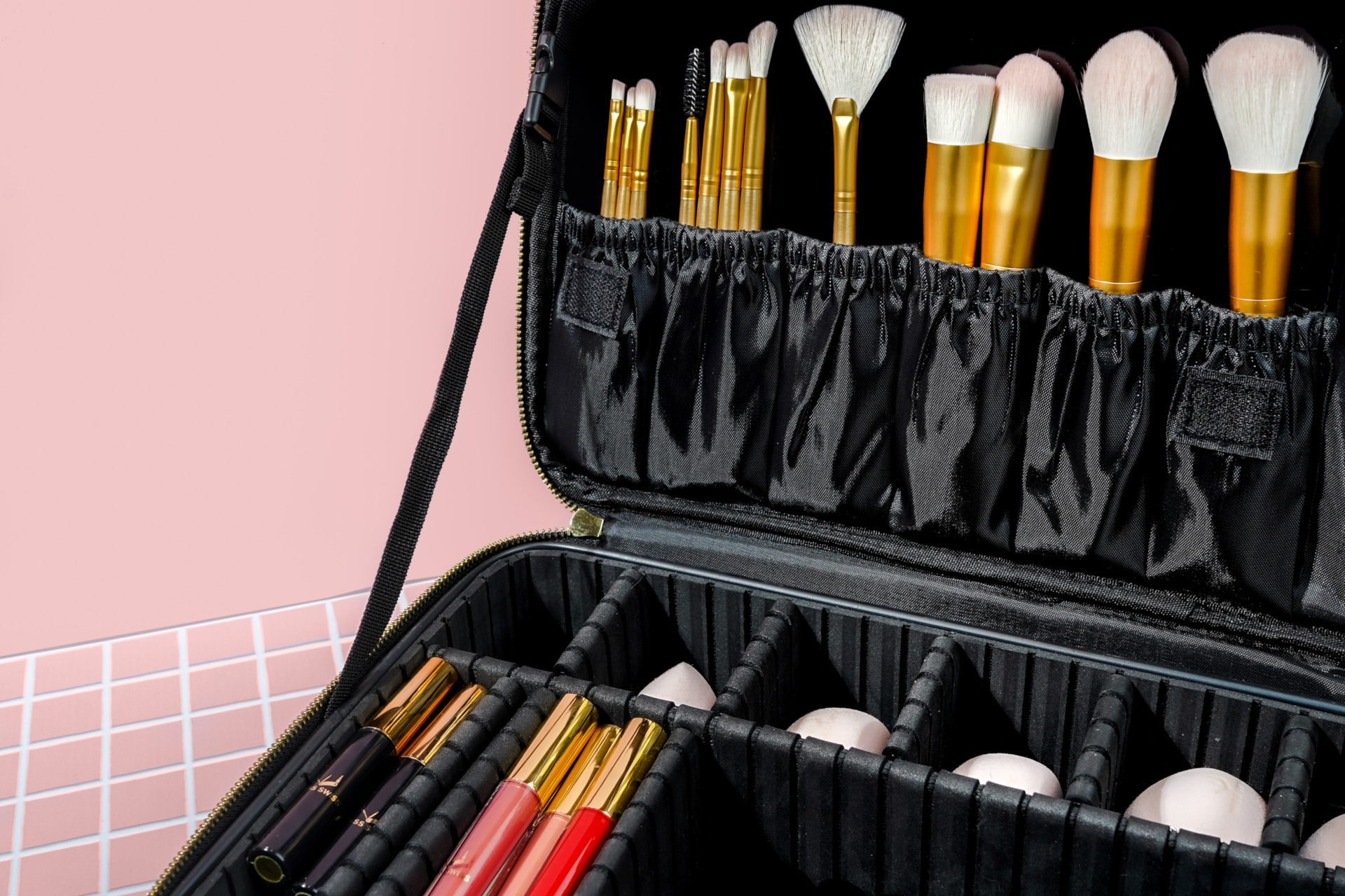 Close up of inside of black makeup case on pink background