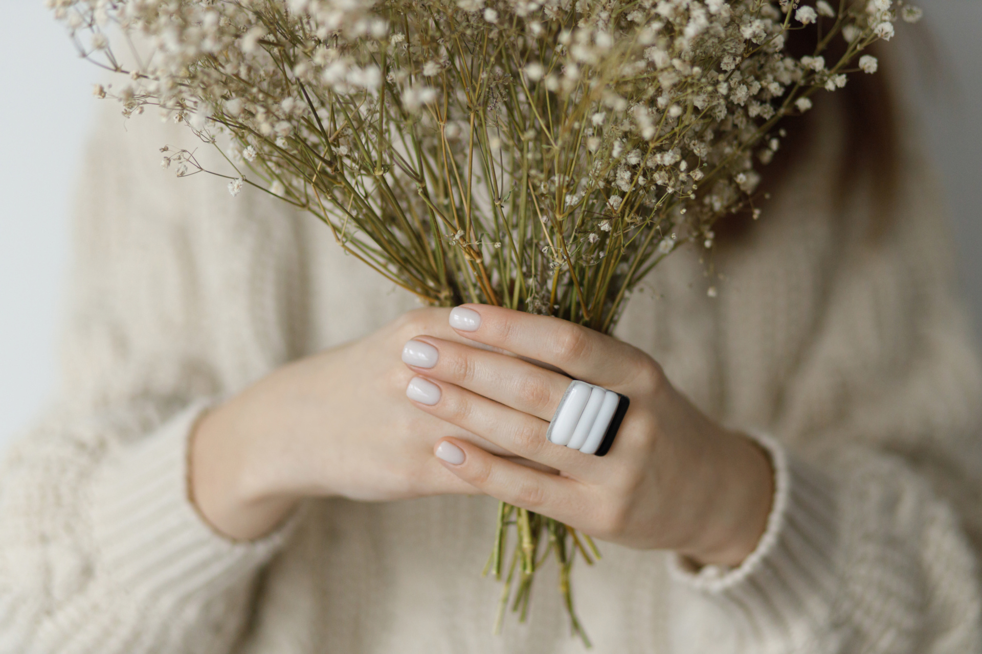 Hands with neutral nail colour holding bouquet