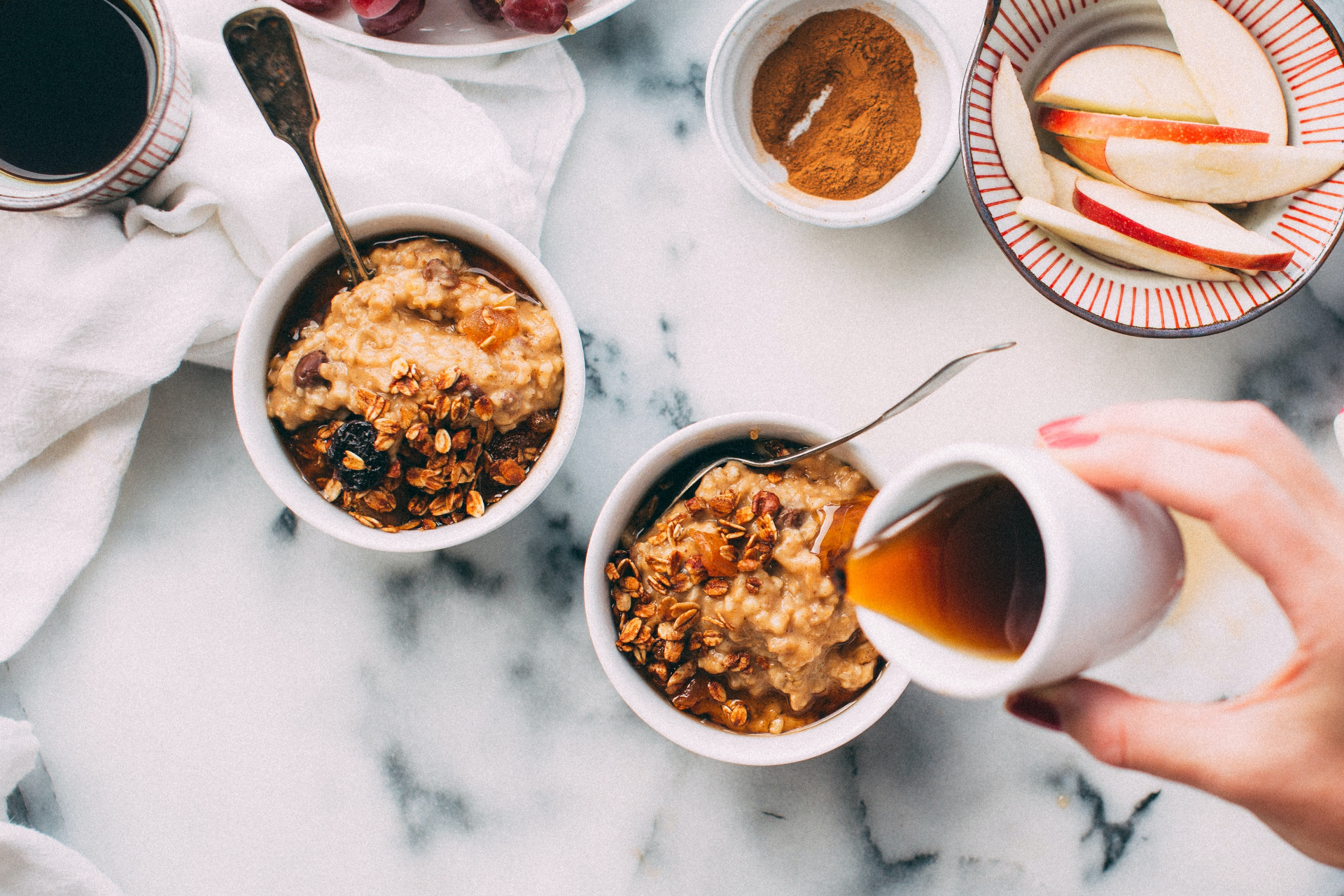 Hand pouring maple syrup on granola