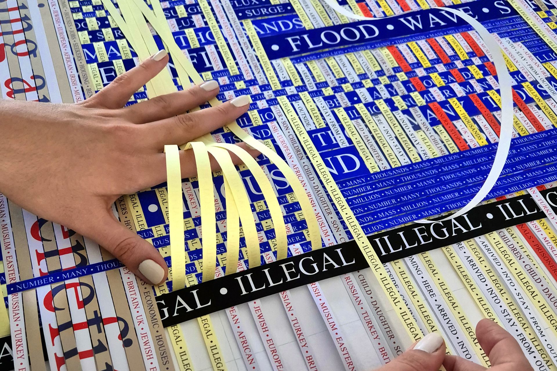 Large paper-woven instllation using strips of paper printed with immigration headlines