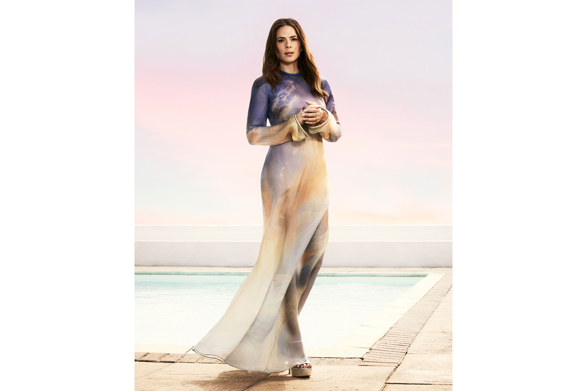 Hayley Atwell stands poolside in long dress