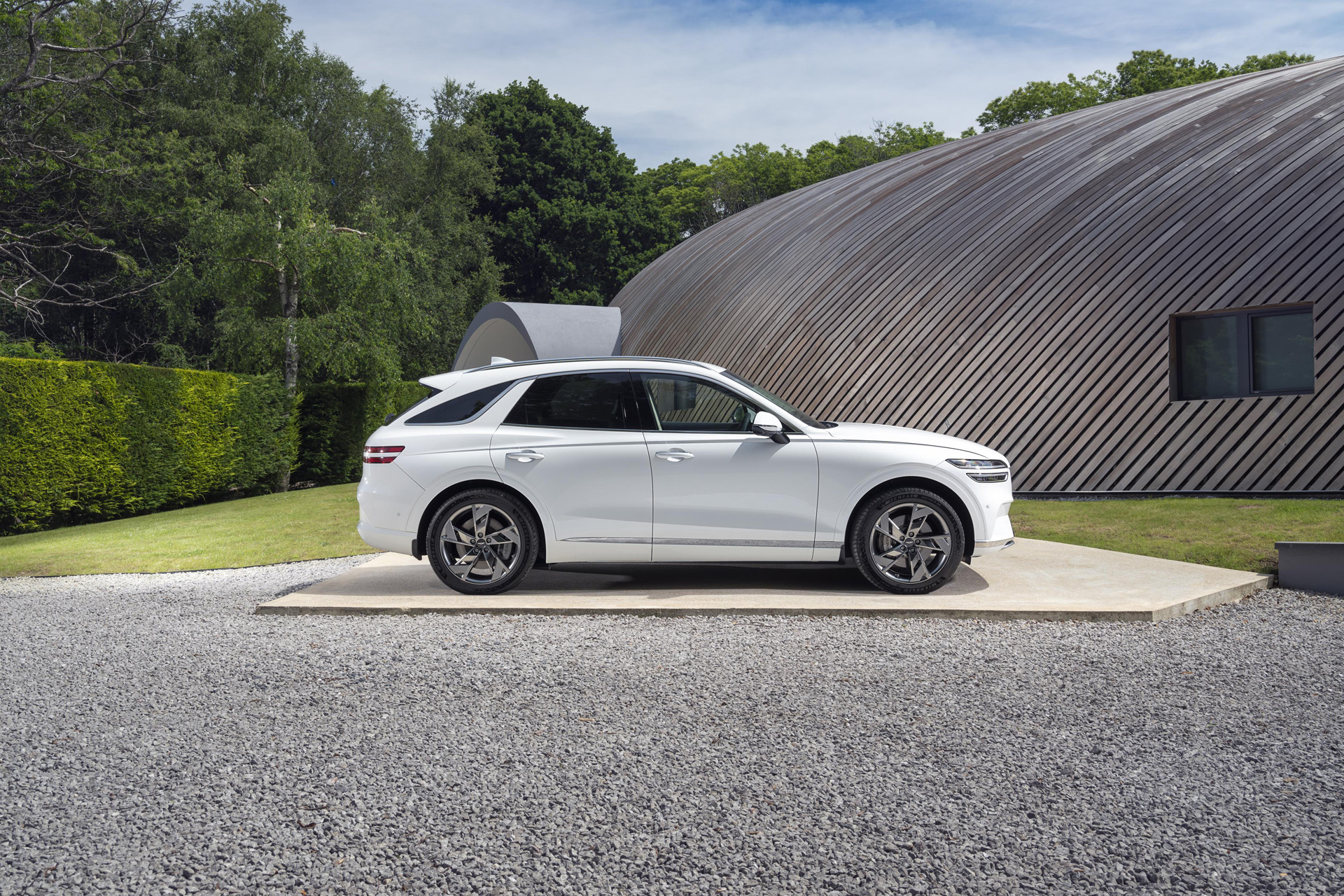 White Electrified GV70 Sport Line next to a modern building