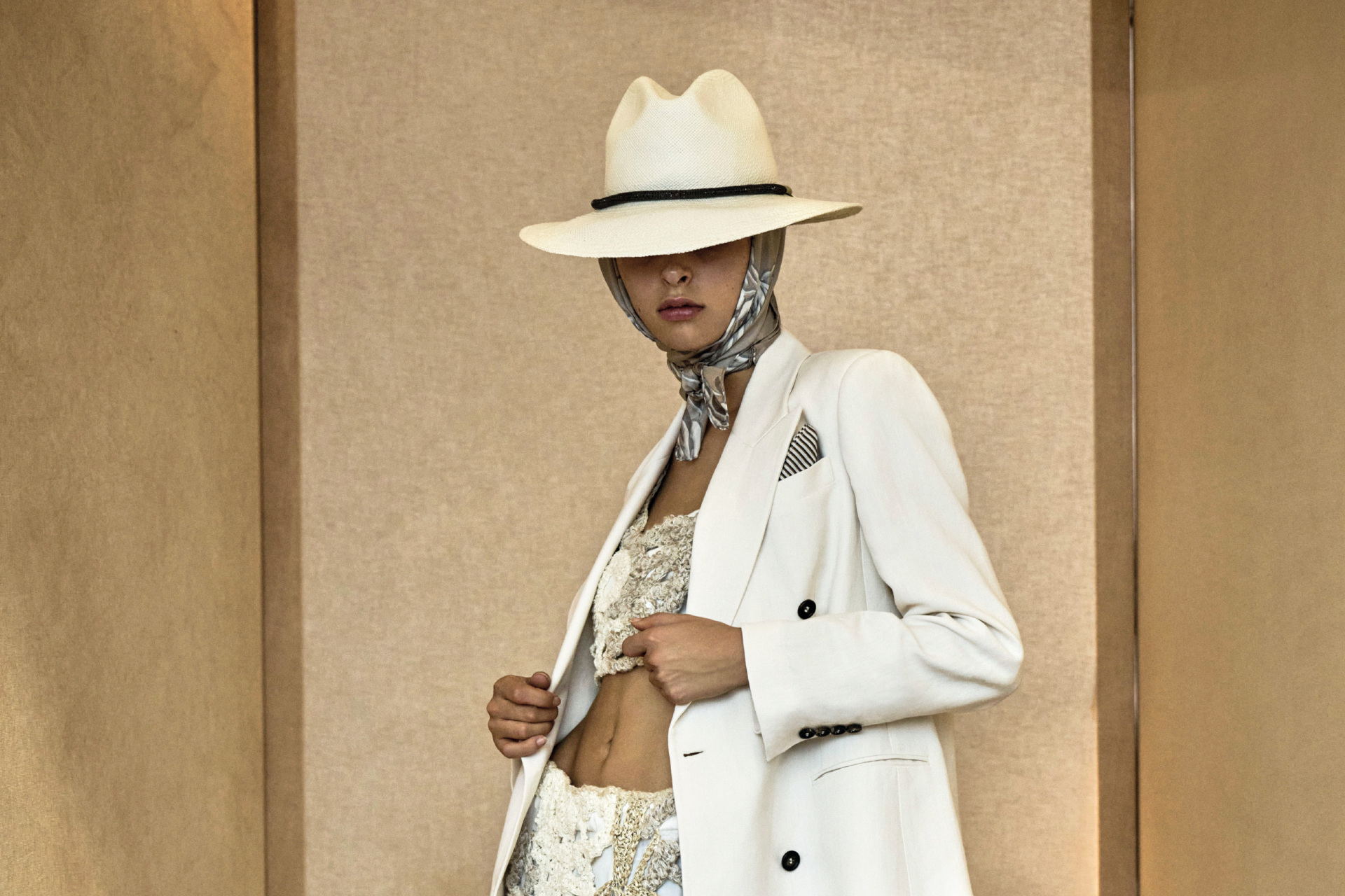 Woman in white hat and suit on gold background