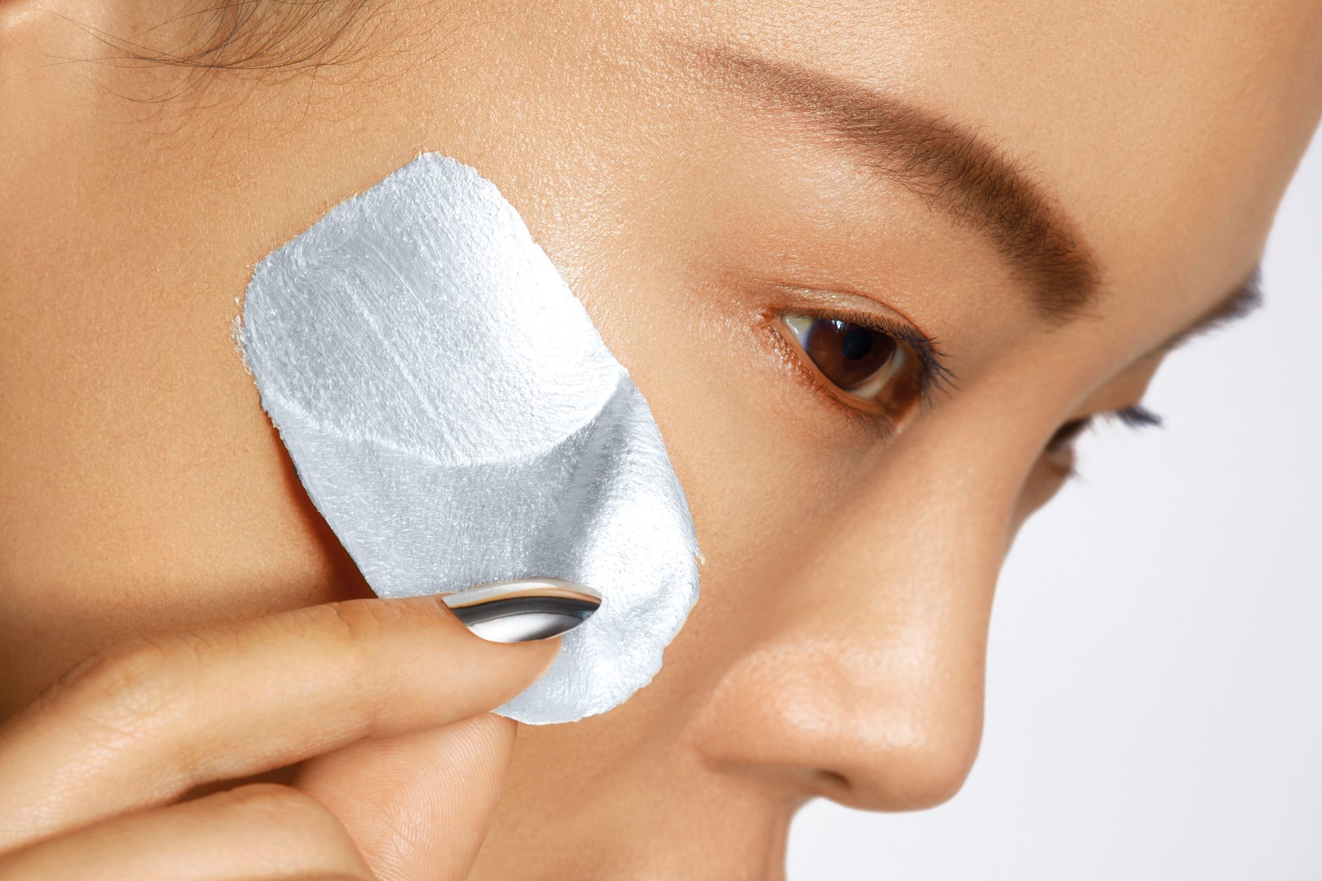 Close up of woman's face peeling silver mask off