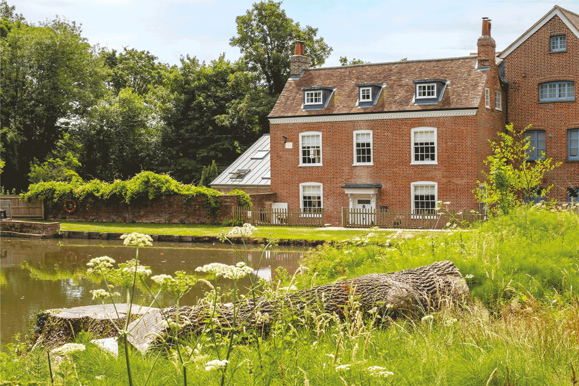 Red brick manor house overlooking a river.