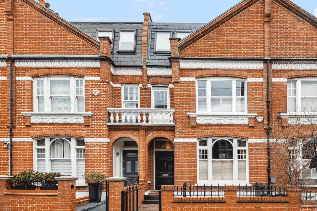 Red brick terraced house with white window frames.