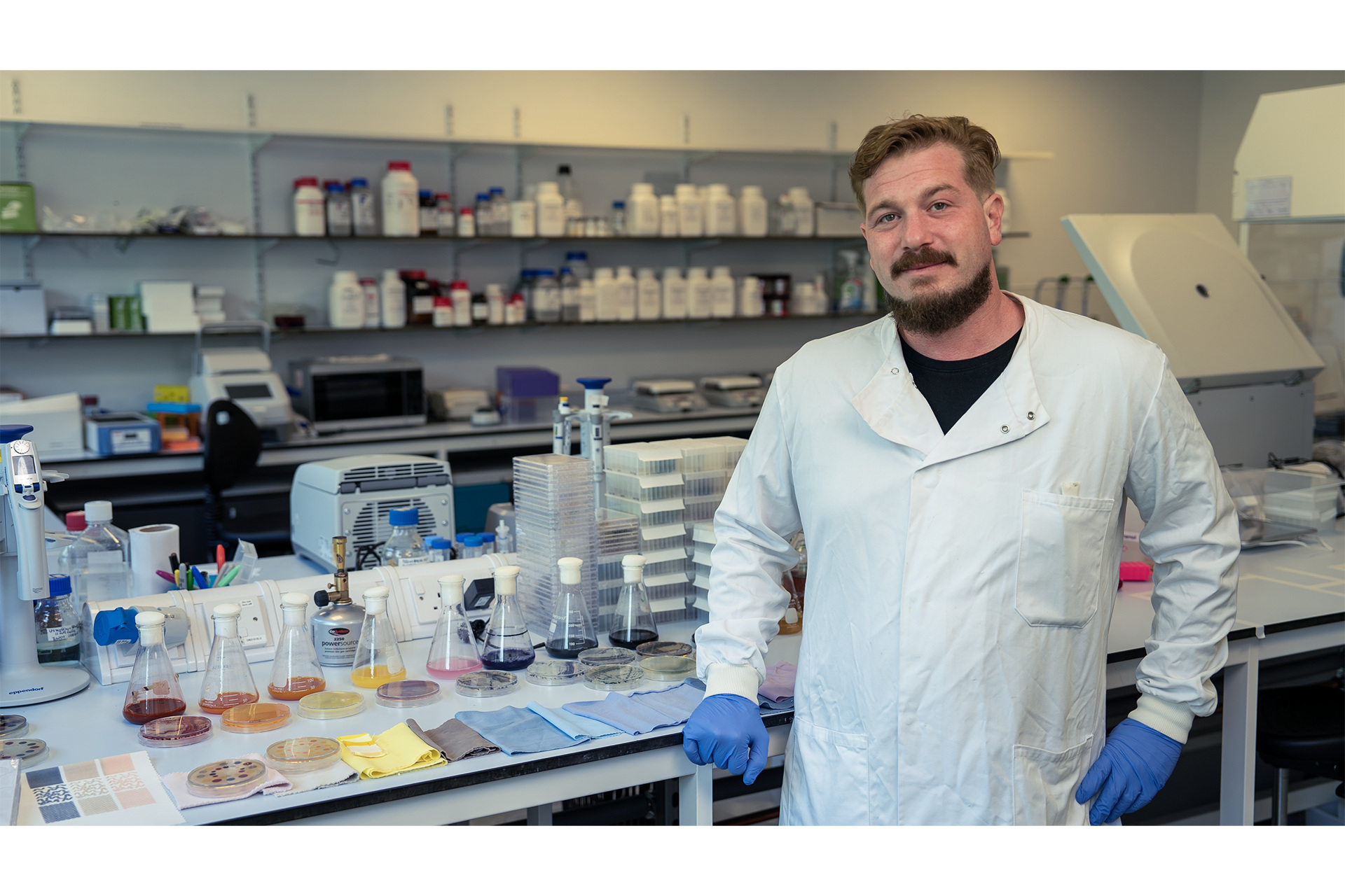 Man in lab coat stood in front of table with colour swatches