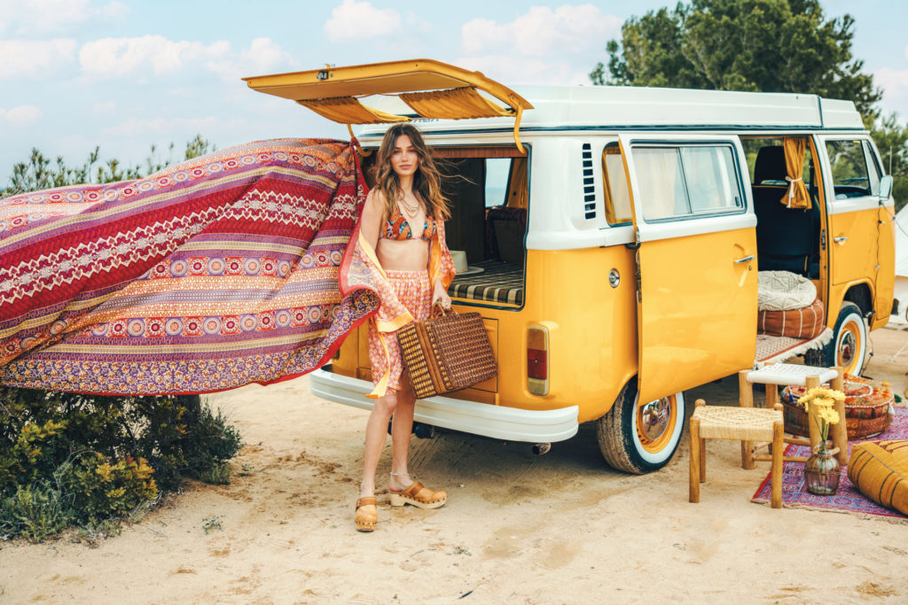 Woman in orange robe stood by campervan