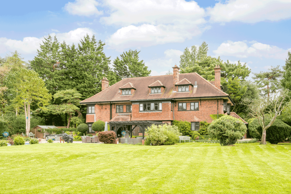 Red brick country home with shrubs in front and lawns surrounding.
