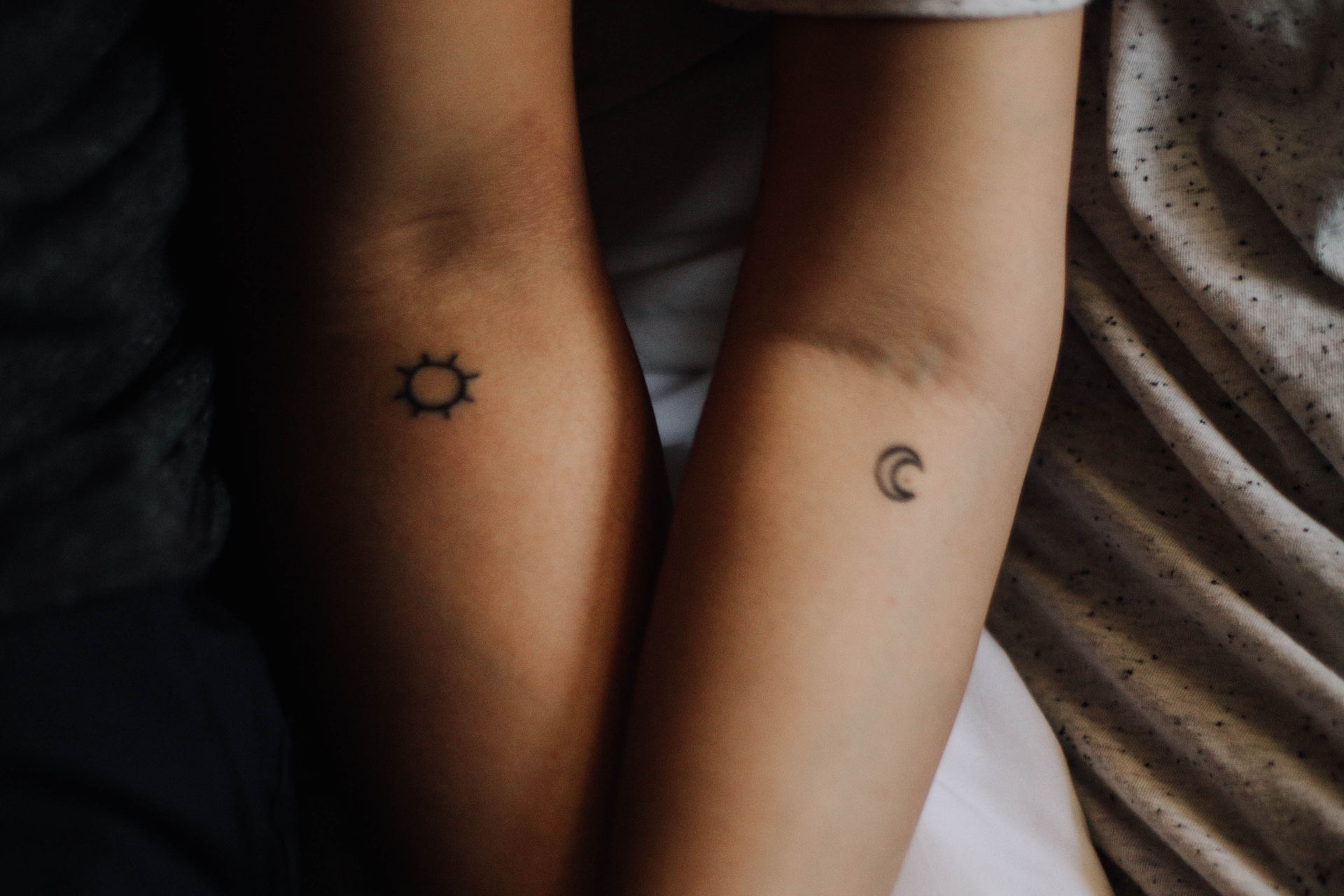 Two arms next to each other with small tattoos