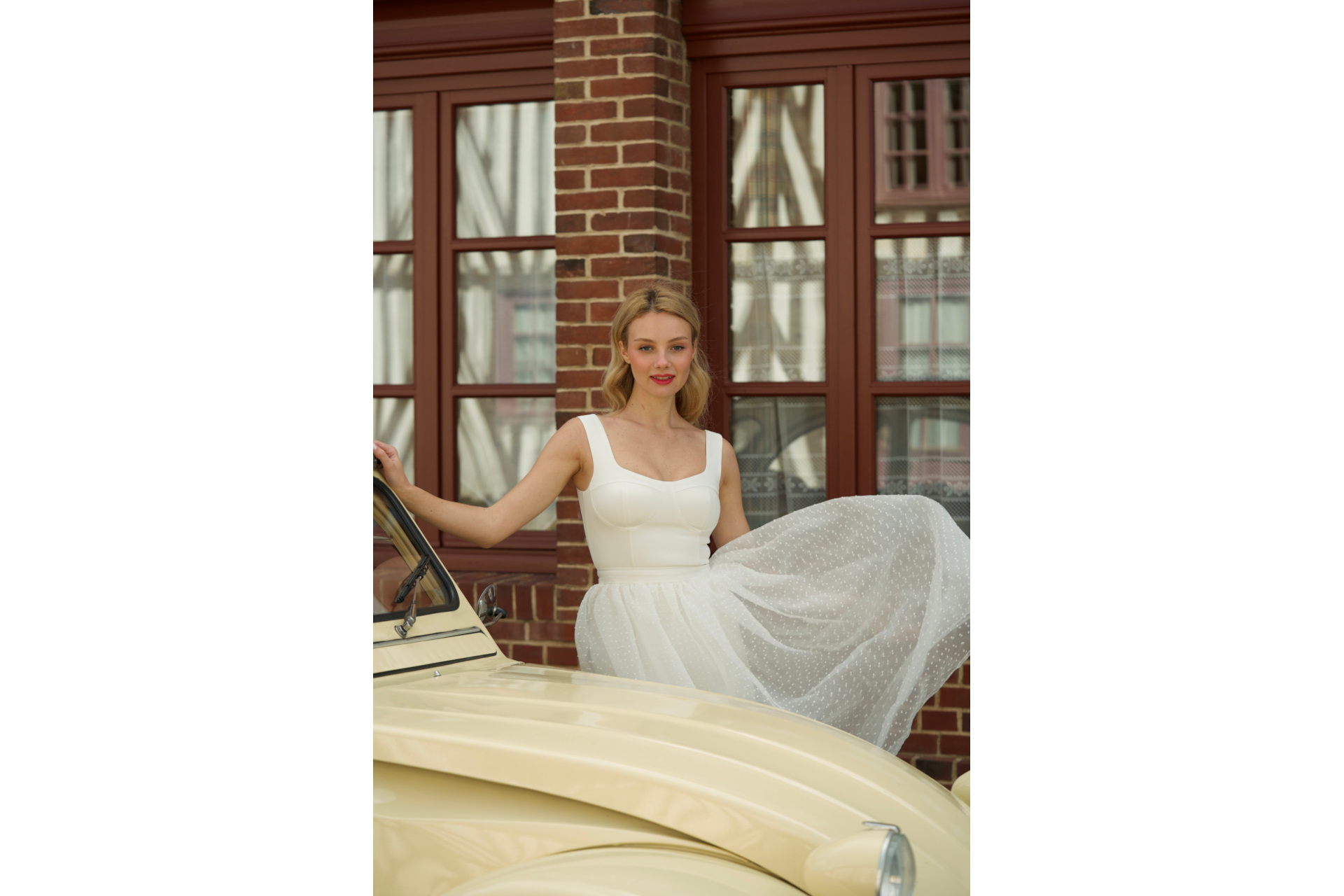 Woman in white dress by pastel yellow car