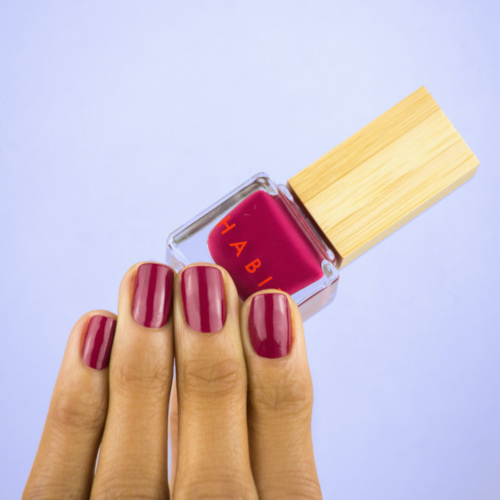 Hand holding red varnish bottle