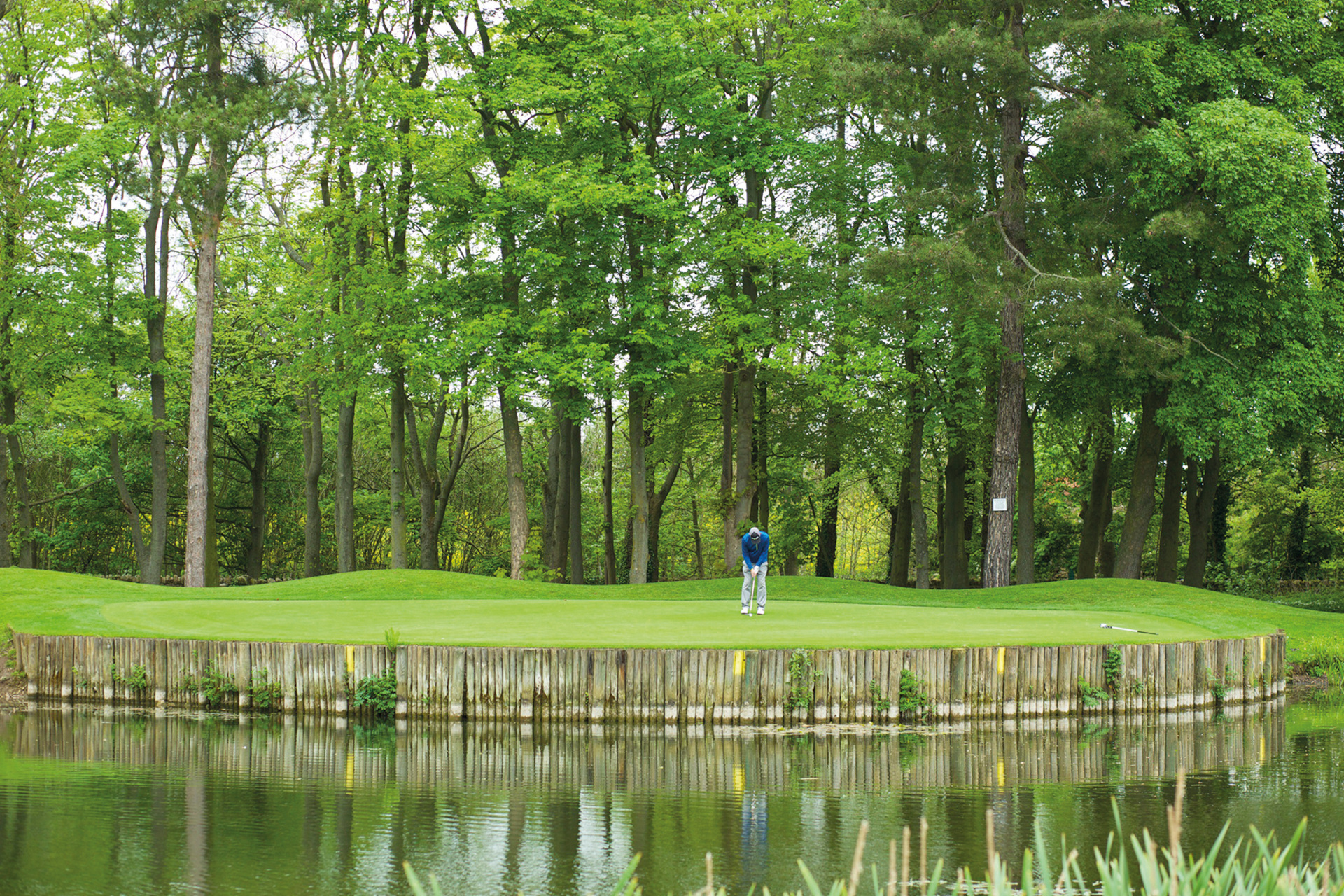 Man playing golf by river