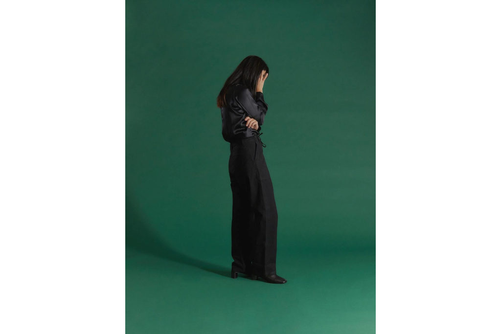 Woman in dark clothes in front of green background