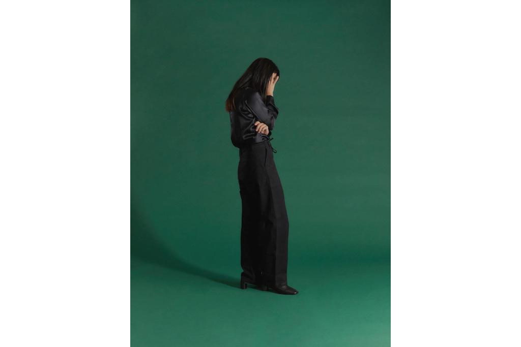 Woman in dark clothes in front of green background