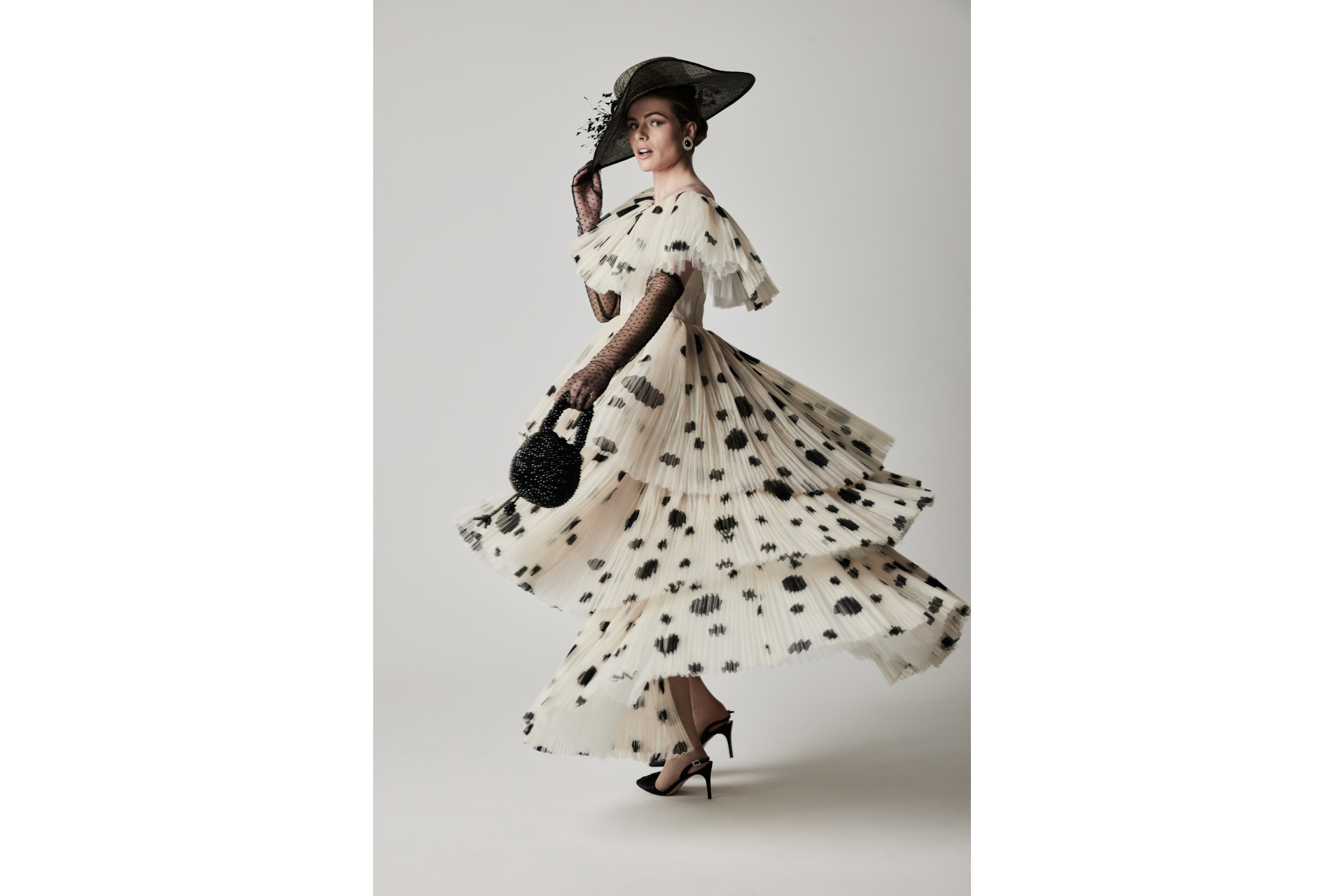 Woman in black and white spotted dress with black hat