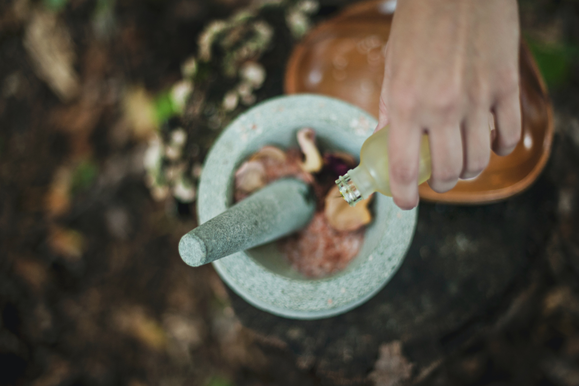 Hand drizzling oil into mortar and pestle