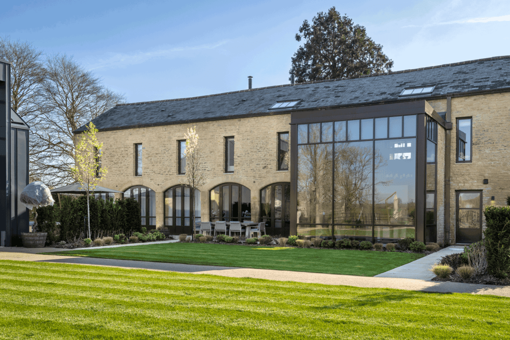 Modern barn with glass extension and warehouse-style downstairs windows.