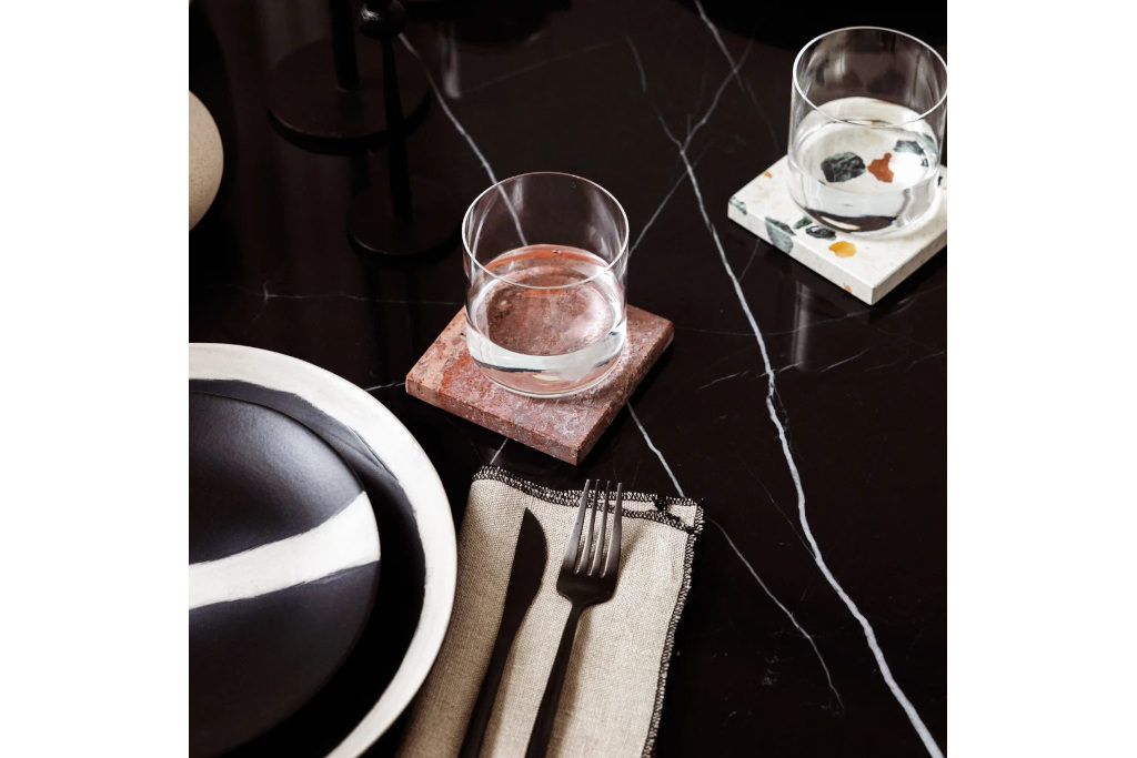 Two glasses on marble coasters on black marble counter