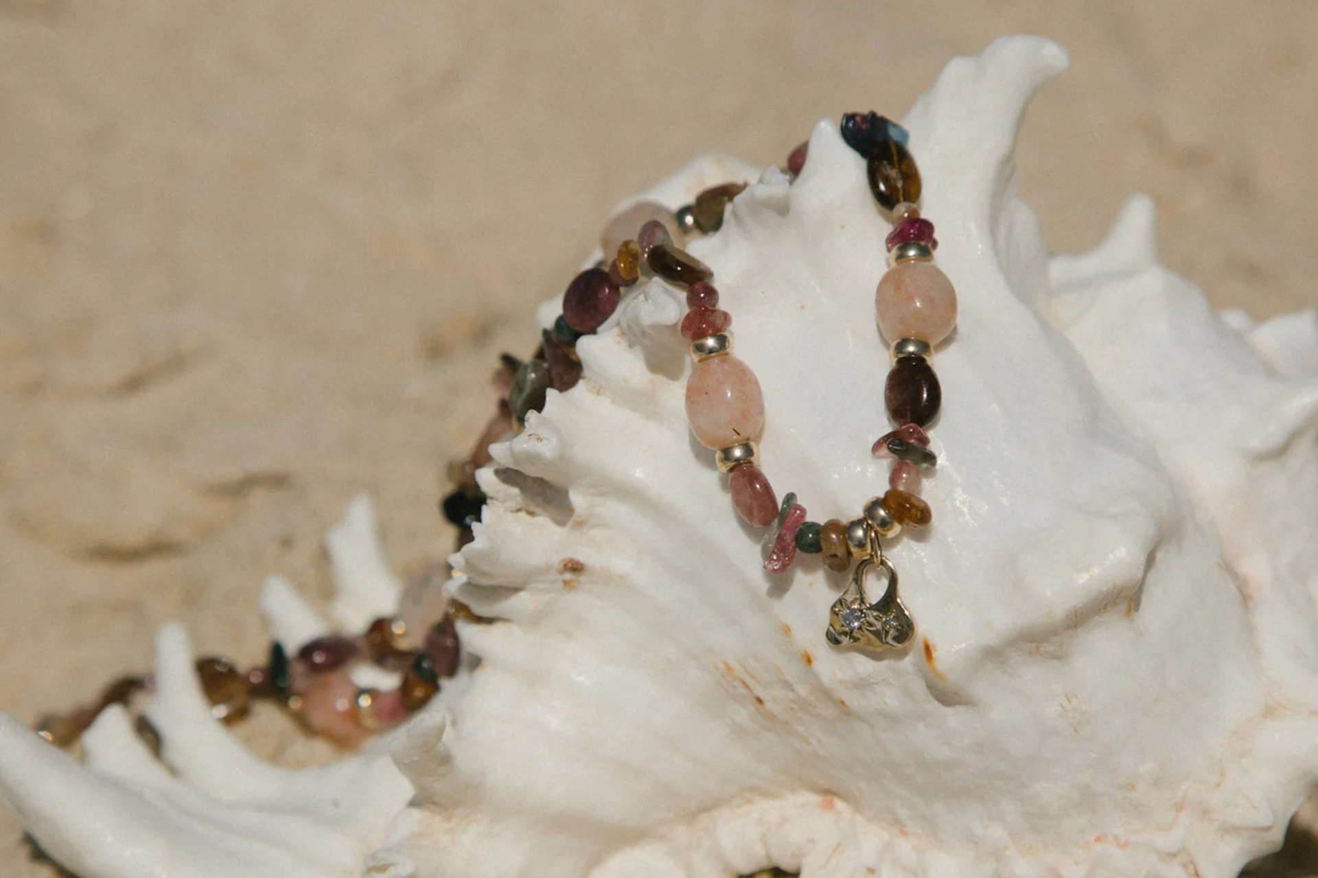 Brown and pink necklace on shell on beach