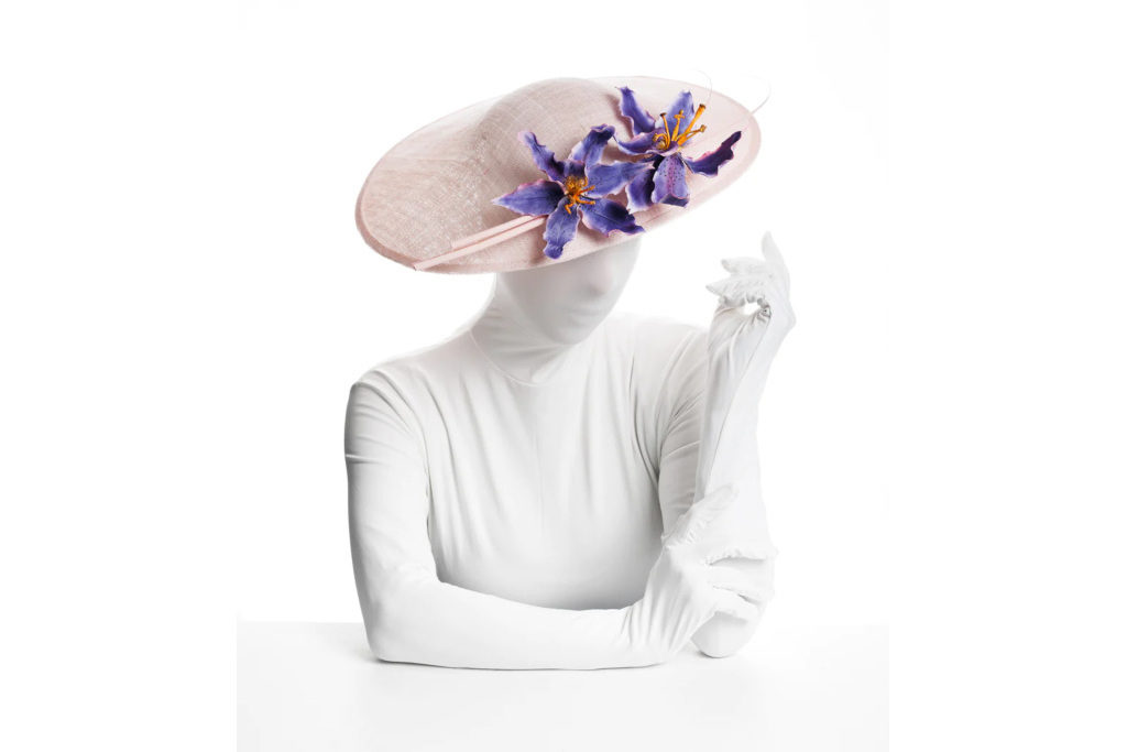 Woman in white suit wearing straw hat with purple flowers