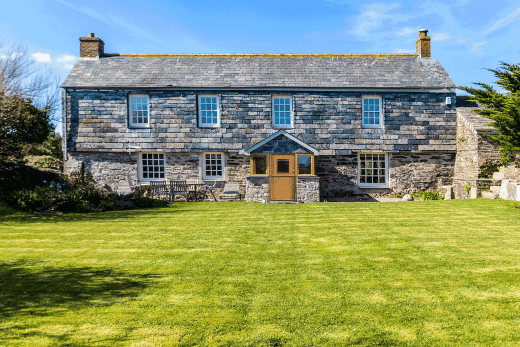 Large farmhouse with wooden door and lawns in front.