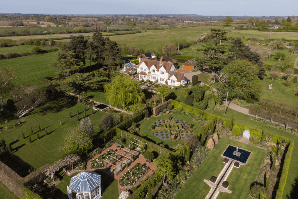 Aerial view of large country home with landscaped gardens and a pergola.