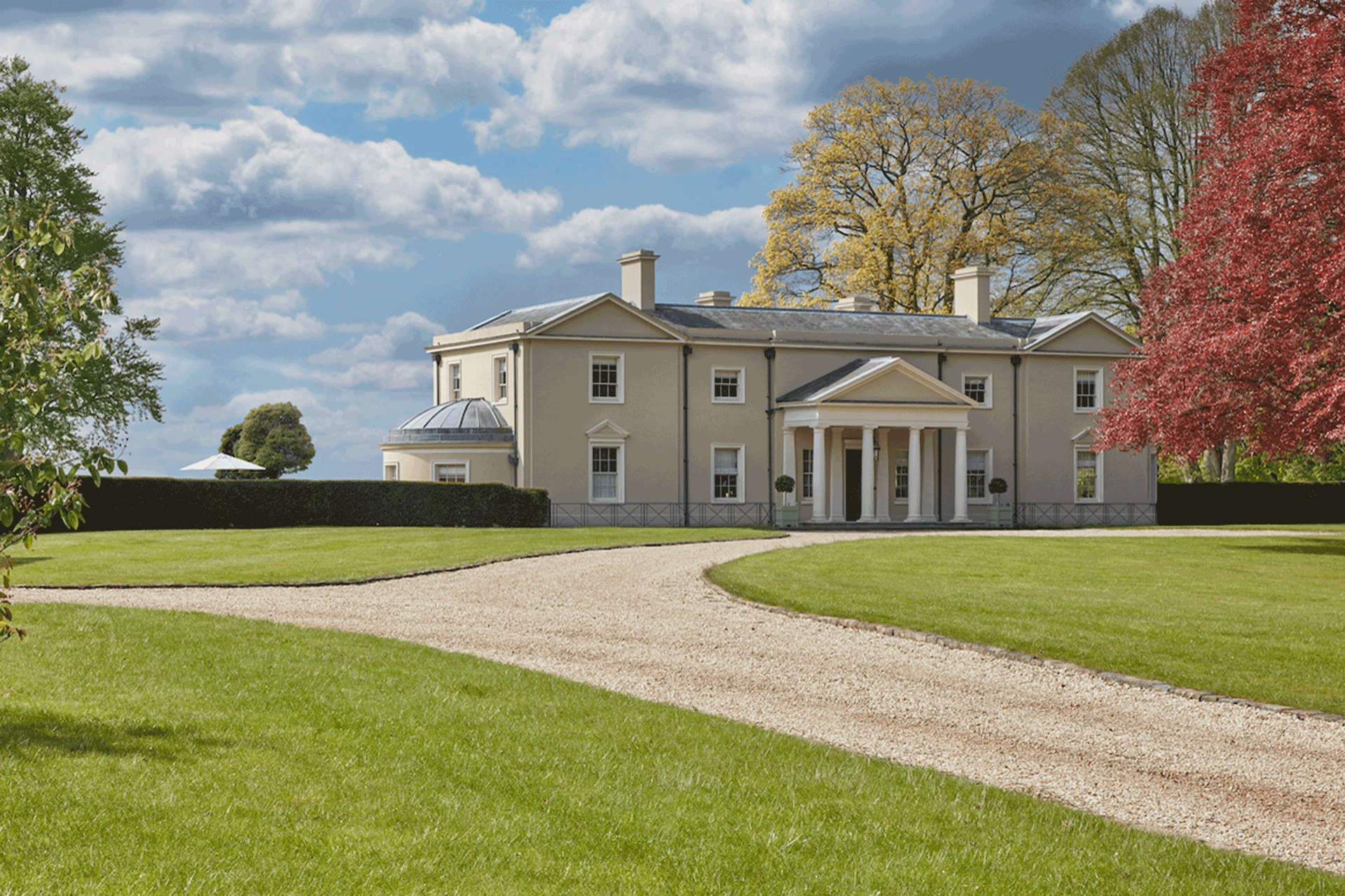 Classical Georgian country manor with central pillars and a domed circular dining room on the left side.